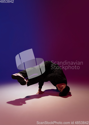 Image of Beautiful sportive boy dancing hip-hop in stylish clothes on colorful gradient background at dance hall in neon light.