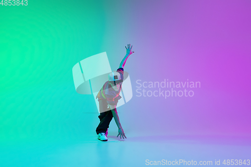 Image of Beautiful sportive boy dancing hip-hop in stylish clothes on colorful gradient background at dance hall in neon light.