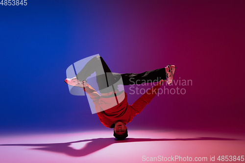 Image of Beautiful sportive boy dancing hip-hop in stylish clothes on colorful gradient background at dance hall in neon light.