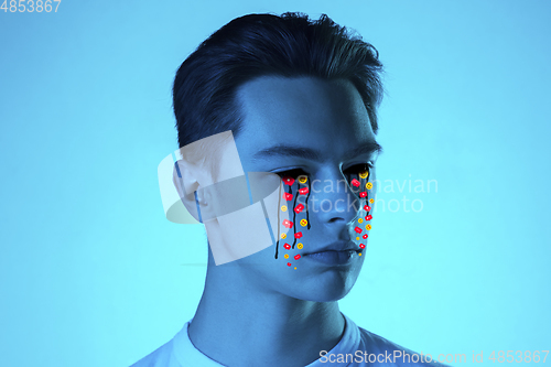 Image of Tears illustrated of social media activity signs on male face in neon light. Real life versus online lifestyle, addiction to modern technologies