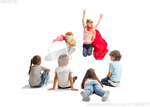 Image of Child pretending to be a superhero with her super dog and friends sitting around