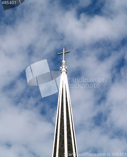 Image of Christian cross atop of church steeple with clouds