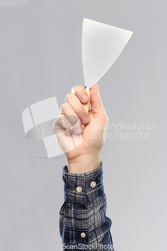 Image of close up of builder's hand holding putty knife