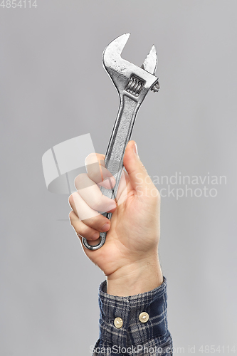 Image of close up of builder's hand holding wrench