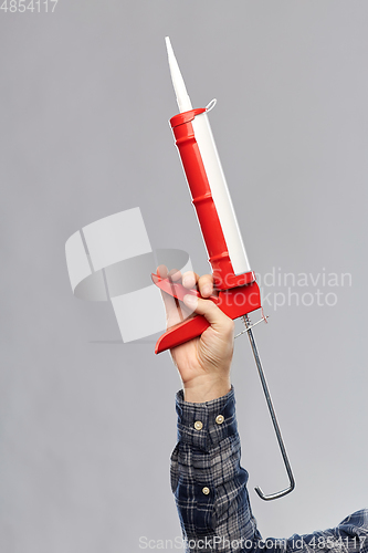 Image of close up of builder's hand holding sealant gun