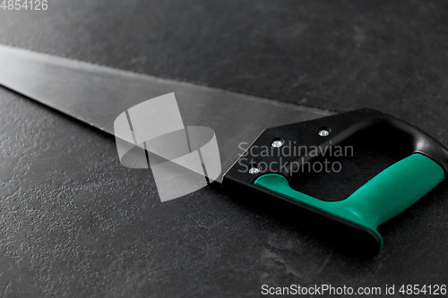 Image of close up of saw on slate background