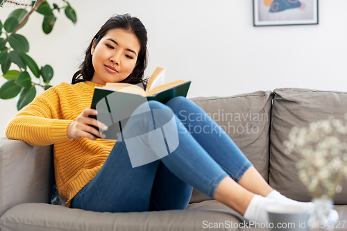 Image of asian young woman reading book at home