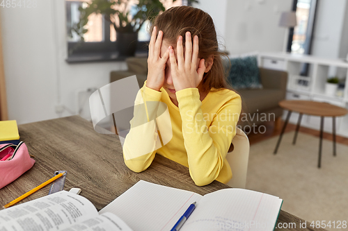 Image of stressed little student girl learning at home