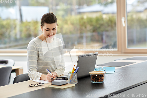 Image of young woman with laptop working at home office