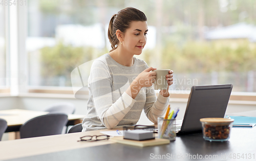 Image of woman with laptop and coffee working at home