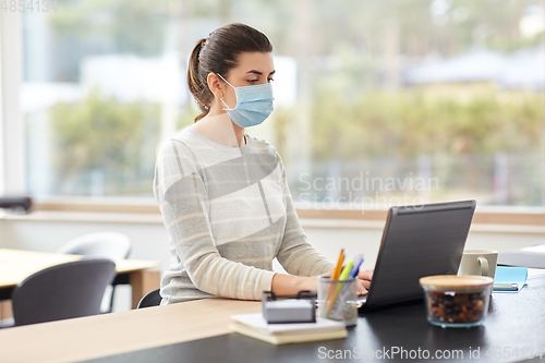 Image of woman in mask with laptop working at home office