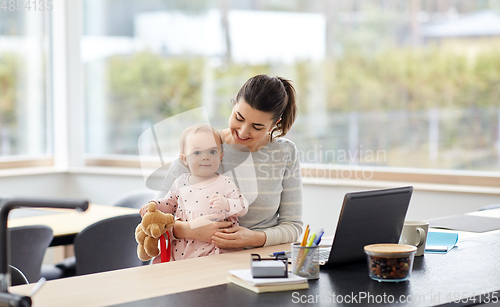 Image of happy mother with baby working at home office