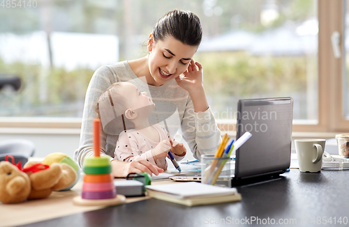 Image of happy mother with baby working at home office