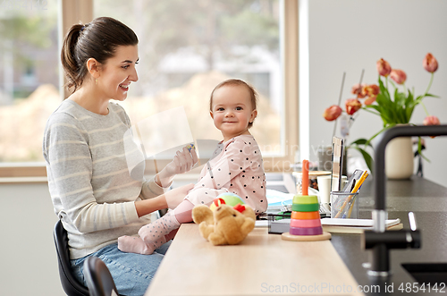 Image of happy mother with baby working at home office