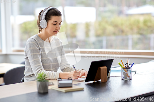 Image of woman in headphones with tablet pc working at home