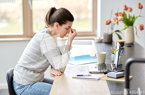 Image of tired woman with laptop working at home office