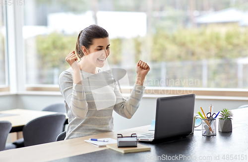 Image of happy woman with laptop working at home office