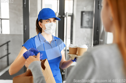 Image of delivery girl in mask giving paper bag to customer