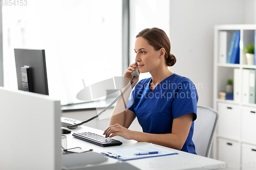 Image of doctor with computer calling on phone at hospital