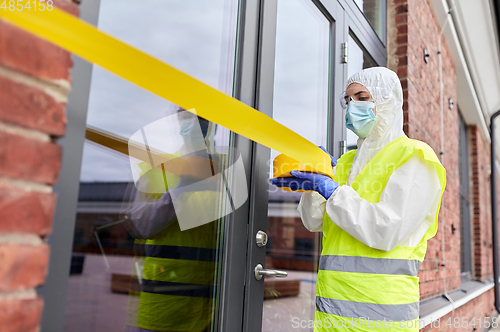 Image of healthcare worker sealing door with caution tape