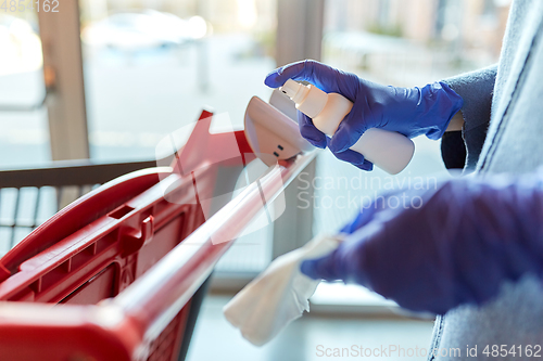 Image of woman cleaning shopping cart handle with sanitizer