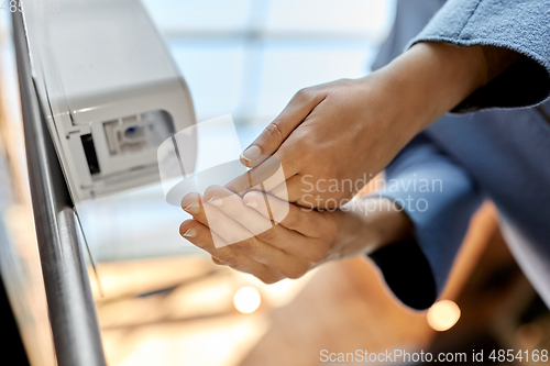 Image of close up of woman at dispenser with hand sanitizer