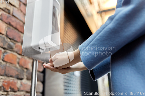 Image of close up of woman at dispenser with hand sanitizer