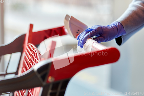 Image of hand cleaning shopping cart handle with wet wipe