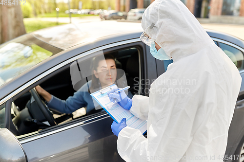 Image of healthcare worker with clipboard and woman in car