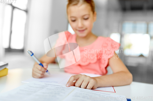 Image of student girl with book writing to notebook at home