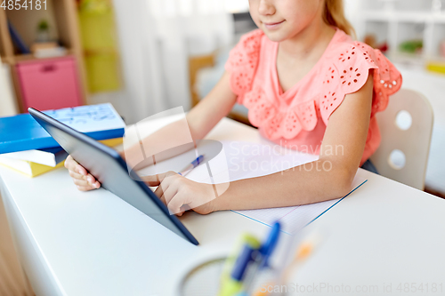 Image of little student girl using tablet computer at home