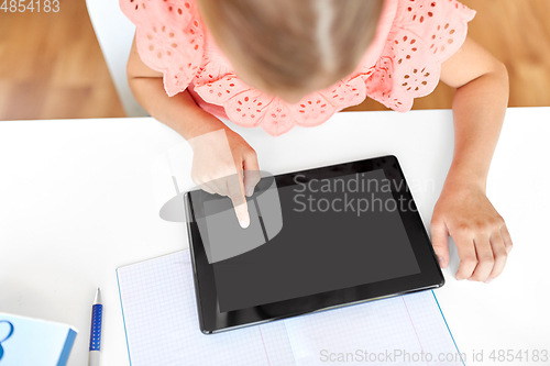 Image of little student girl using tablet computer at home