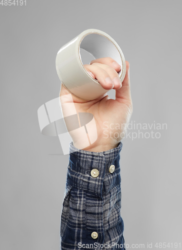 Image of close up of builder's hand holding adhesive tape