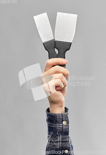 Image of close up of builder's hand holding putty knives