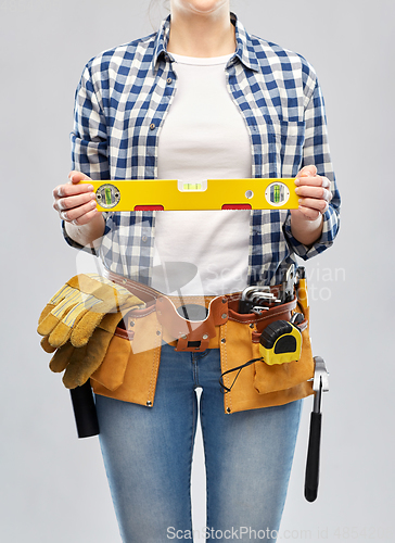 Image of woman builder with level and working tools on belt