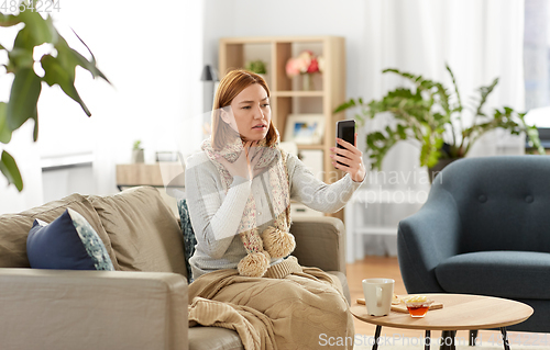 Image of sick woman having video call on phone at home