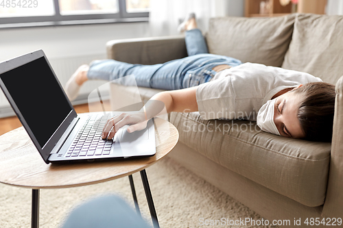 Image of sick bored woman with laptop lying on sofa at home