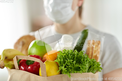 Image of woman in mask with food in paper bag at home