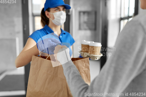 Image of delivery girl in mask giving paper bag to woman