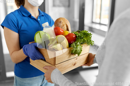 Image of delivery woman in mask giving food to customer