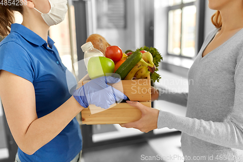 Image of delivery woman in mask giving food to customer