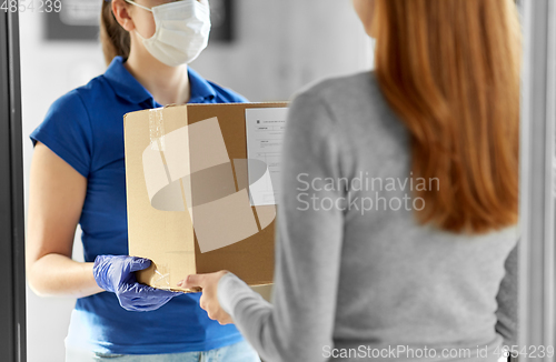 Image of delivery girl in face mask giving parcel to woman