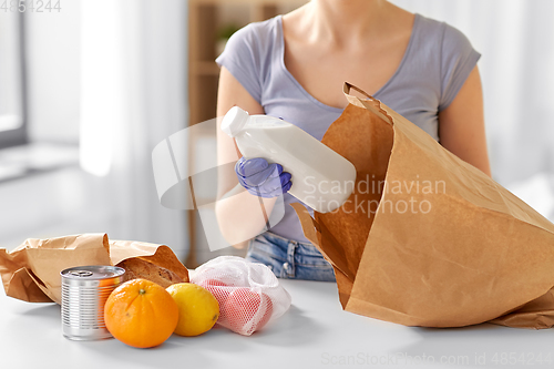 Image of woman in gloves taking food from paper bag at home