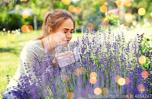 Image of young woman smelling lavender flowers in garden