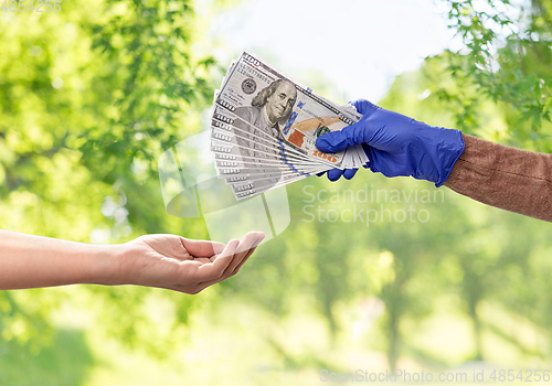 Image of close up of hand in medical glove giving money