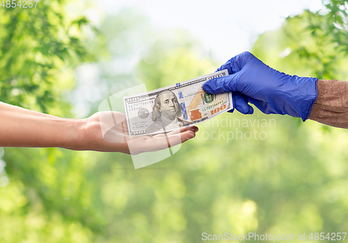 Image of close up of hand in medical glove giving money