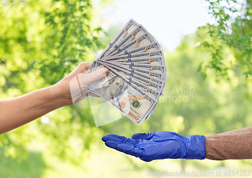 Image of close up of hand in medical glove giving money