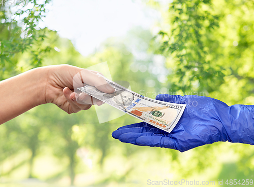 Image of close up of hand in medical glove giving money