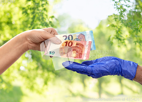 Image of close up of hand in medical glove giving money