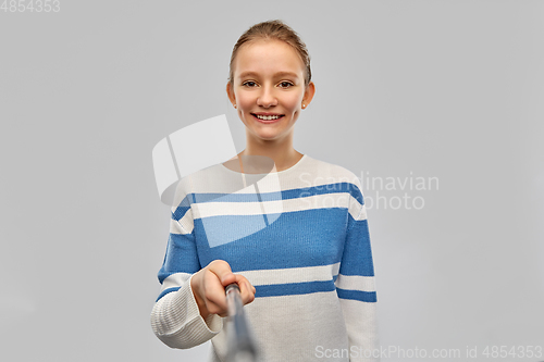 Image of smiling teenage girl in pullover taking selfie